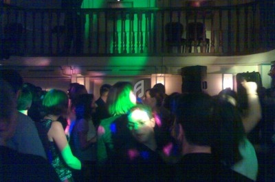 Personnes dansant sous des lumières colorées dans une salle avec une mezzanine en arrière-plan.