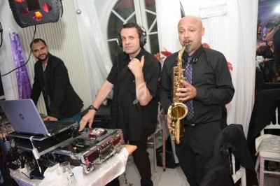 Un DJ mixe de la musique tandis qu'un saxophoniste joue à ses côtés lors d'un événement en intérieur.