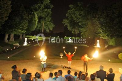 Salle décorée pour un événement avec un piano au premier plan, des chaises rouges alignées et des arrangements floraux.