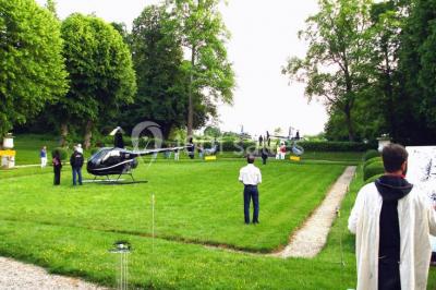 Salle décorée pour un événement avec un piano au premier plan, des chaises rouges alignées et des arrangements floraux.