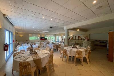 Cuisine professionnelle avec plan de travail en inox, cuisinières, hotte d'extraction et murs carrelés blancs.