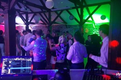 Des personnes dansent dans une salle éclairée par des lumières colorées, avec une table de DJ au premier plan.