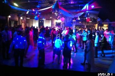 Des personnes dansent sous des lumières colorées dans une salle décorée pour une fête ou un événement festif.