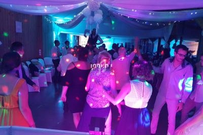 Personnes dansant sous des lumières colorées dans une salle décorée pour un événement festif.