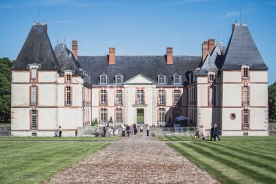 Château éclairé sous un ciel nocturne avec une pleine lune visible en arrière-plan.