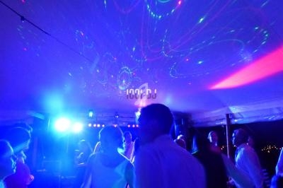 Personnes dansant sous des lumières colorées dans une ambiance festive sous une tente éclairée.