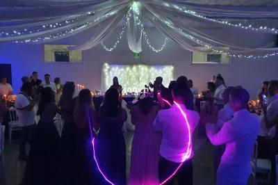 Des invités dansent en cercle sous un plafond décoré de guirlandes lumineuses dans une salle de réception.