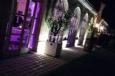 Façade d'un bâtiment éclairé de nuit avec des arches vitrées et une lumière violette à l'intérieur.