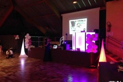 Salle de réception avec éclairage coloré, écran de projection et matériel de sonorisation installé sur une scène.