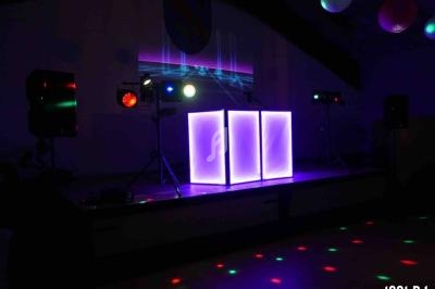 Installation de matériel de DJ avec éclairage coloré et jeux de lumière dans une salle sombre.
