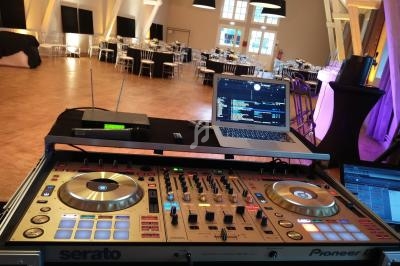 Console de mixage DJ avec ordinateur portable dans une salle de réception préparée pour un événement.