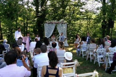 Cérémonie de mariage en plein air avec des invités assis, un couple devant un autel décoré de fleurs.