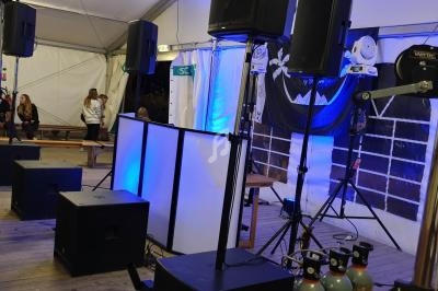 Installation de matériel audio et éclairage dans une tente, avec des enceintes, projecteurs et décorations.