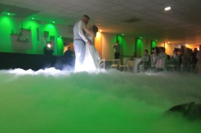 Un couple danse au milieu d'une salle éclairée de lumières vertes, entouré d'un effet de fumée au sol.
