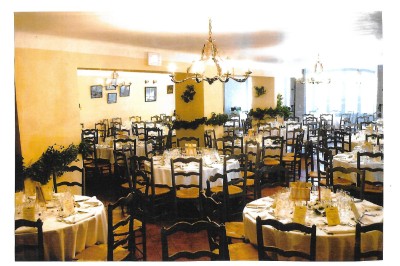 Table dressée pour un repas avec nappes blanches, couverts, verres, menus, pains, bouteille de vin et seau à glace.