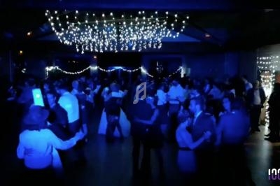 Salle sombre avec des guirlandes lumineuses au plafond, des personnes dansant et discutant lors d'un événement festif.