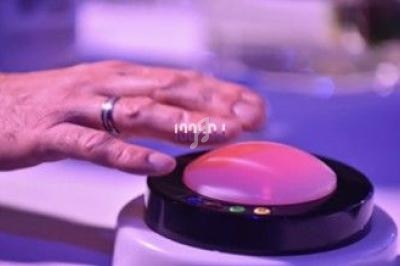 Une main posée sur un bouton lumineux rond, entouré d'une lumière tamisée violette.