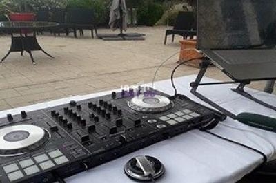 Table de mixage DJ avec platines et ordinateur portable installés en extérieur sur une table blanche.
