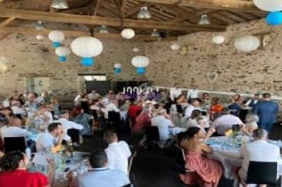 Salle en pierre décorée de lanternes blanches et bleues, remplie de convives assis à des tables lors d'un événement.
