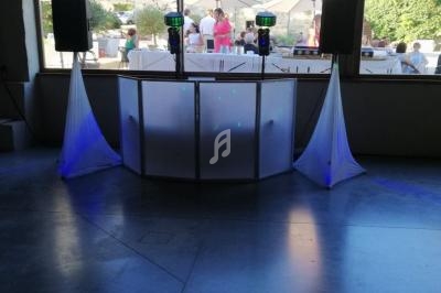 Console de DJ avec platines et équipement audio, installée sous une tente lors d'un événement en extérieur.