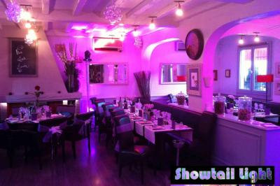 Des personnes dansent dans une salle sombre éclairée par des faisceaux lumineux colorés et des effets laser.