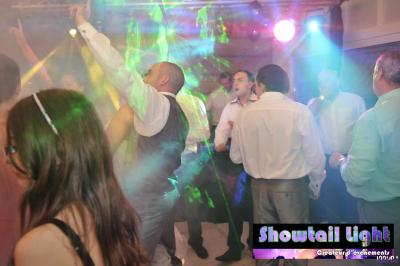 Des personnes dansent dans une salle sombre éclairée par des faisceaux lumineux colorés et des effets laser.