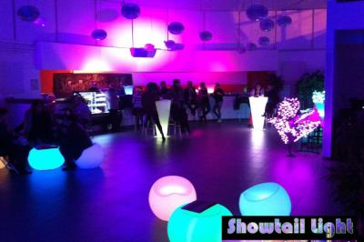 Des personnes dansent dans une salle sombre éclairée par des faisceaux lumineux colorés et des effets laser.