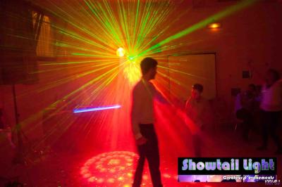 Des personnes dansent dans une salle sombre éclairée par des faisceaux lumineux colorés et des effets laser.