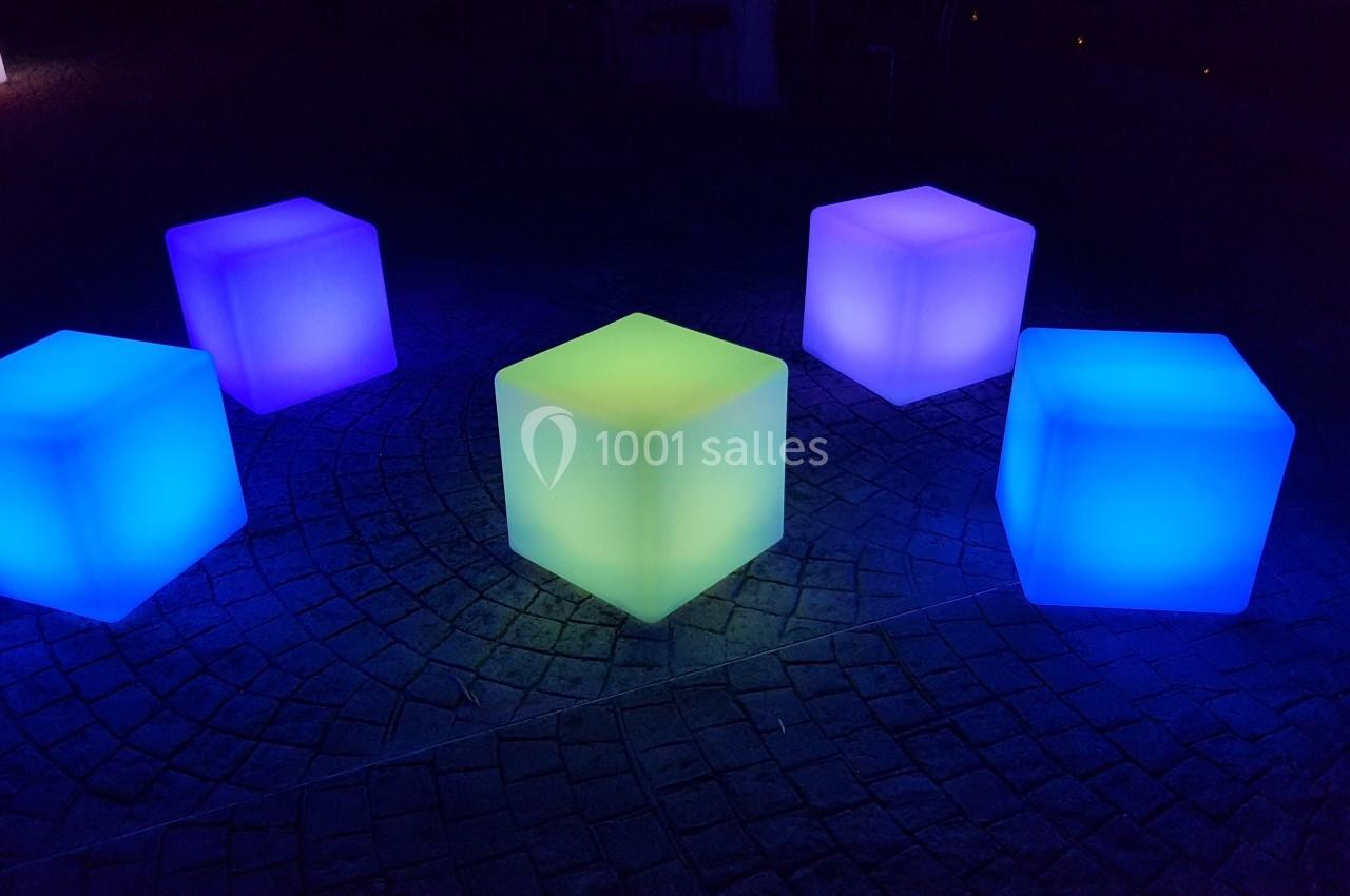Cubes lumineux colorés disposés sur un sol pavé, éclairés dans l'obscurité.