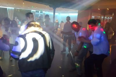 Des personnes dansent dans une salle sombre éclairée par des faisceaux lumineux colorés et des effets laser.