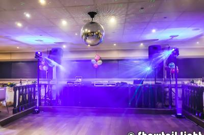 Des personnes dansent dans une salle sombre éclairée par des faisceaux lumineux colorés et des effets laser.