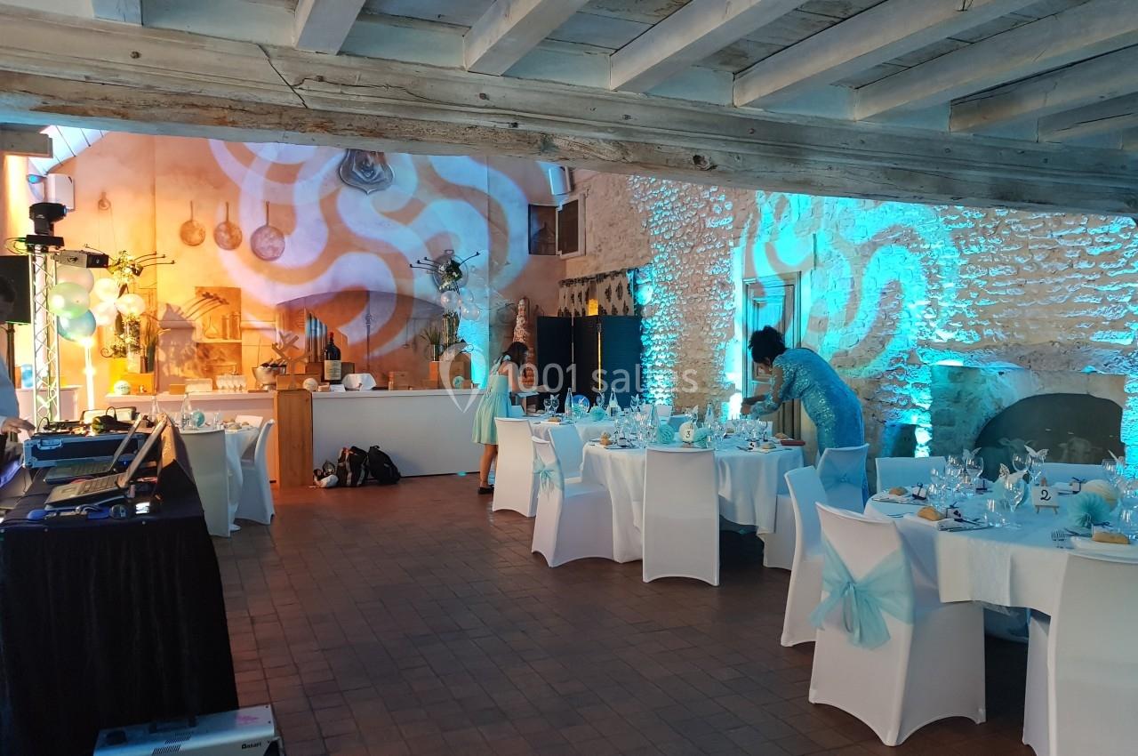 Salle de réception décorée avec des tables dressées, éclairage bleu et ambiance festive en préparation.