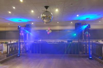 Des personnes dansent dans une salle sombre éclairée par des faisceaux lumineux colorés et des effets laser.