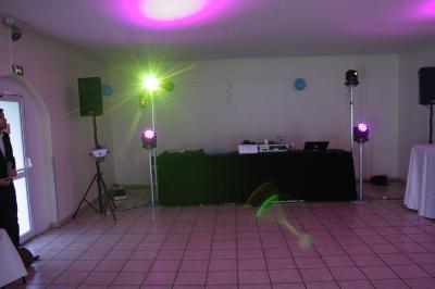 Des personnes dansent dans une salle sombre éclairée par des faisceaux lumineux colorés et des effets laser.