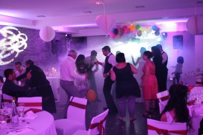 Des personnes dansent dans une salle sombre éclairée par des faisceaux lumineux colorés et des effets laser.