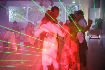 Des personnes dansent dans une salle sombre éclairée par des faisceaux lumineux colorés et des effets laser.