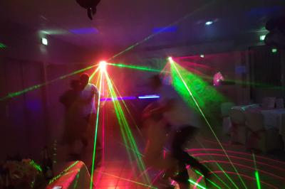 Des personnes dansent dans une salle sombre éclairée par des faisceaux lumineux colorés et des effets laser.