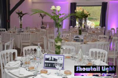 Cube lumineux coloré disposé sur une terrasse en soirée, près d'une tente blanche et d'une table dressée.