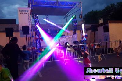Cube lumineux coloré disposé sur une terrasse en soirée, près d'une tente blanche et d'une table dressée.