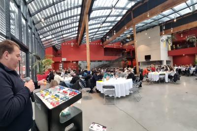 Cube lumineux coloré disposé sur une terrasse en soirée, près d'une tente blanche et d'une table dressée.
