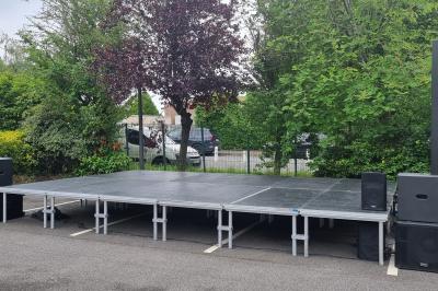 Cube lumineux coloré disposé sur une terrasse en soirée, près d'une tente blanche et d'une table dressée.