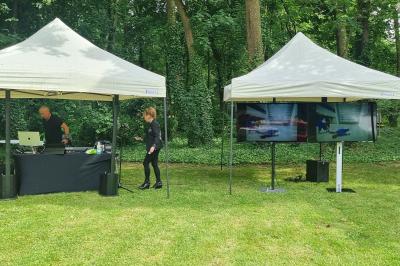 Cube lumineux coloré disposé sur une terrasse en soirée, près d'une tente blanche et d'une table dressée.