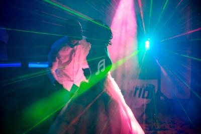 Deux personnes dansent sous des lumières colorées et des faisceaux laser dans une ambiance festive.