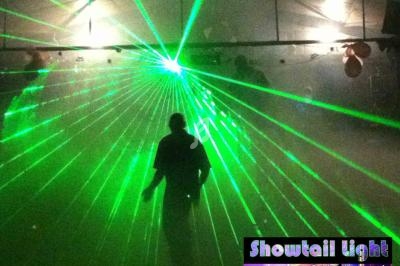Un homme debout dans une salle sombre, éclairée par des faisceaux laser verts.