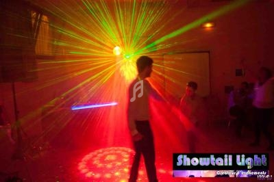 Homme dansant sous des lumières colorées et des effets laser dans une salle sombre.