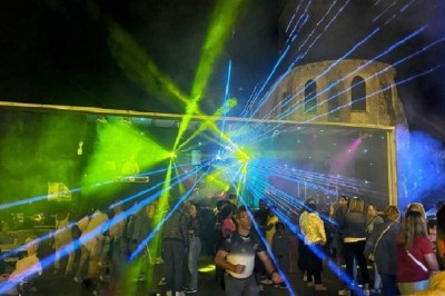 Salle de réception décorée avec des tables rondes, nappes blanches, chaises transparentes et éclairage rose.
