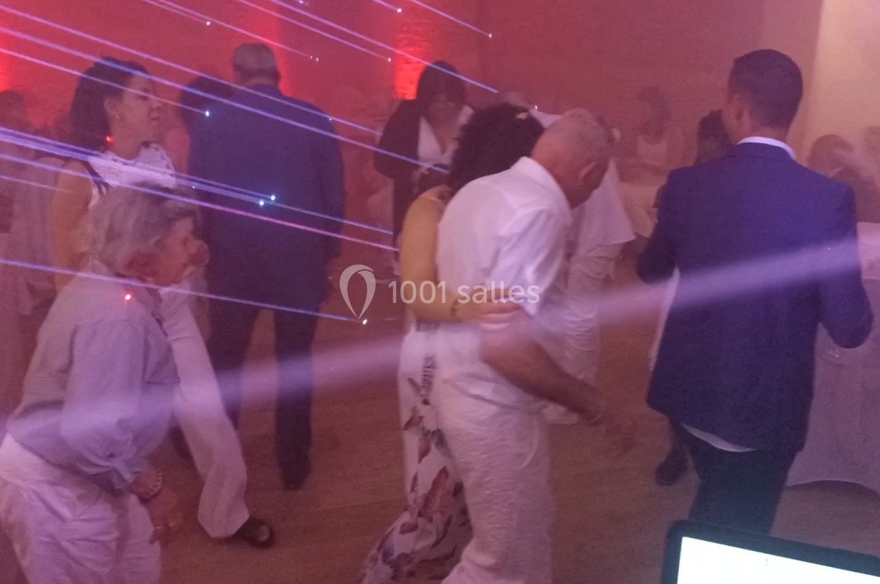 Personnes dansant dans une salle éclairée par des lumières colorées et des faisceaux lumineux.