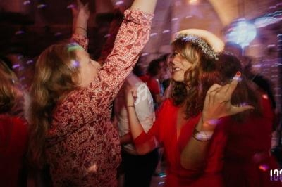 Personnes dansant dans une ambiance festive avec éclairages colorés dans une salle en briques.