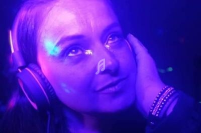 Femme portant un casque audio, éclairée par des lumières violettes et bleues, regardant vers le haut.