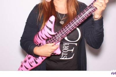 Femme tenant une guitare gonflable rose avec un motif zébré, vêtue d'un haut noir et d'un collier en forme de cœur.